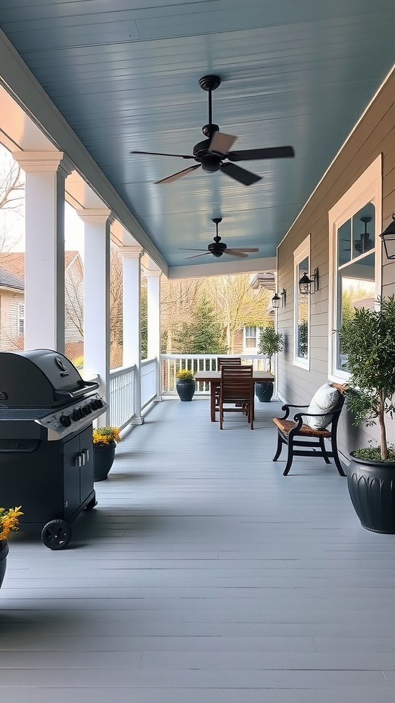 A spacious covered porch with a blue ceiling, featuring a black ceiling fan, a barbecue grill, potted plants, and outdoor furniture including a bench and a wooden dining set.